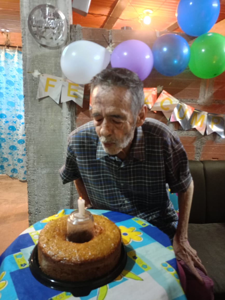 Adulto mayor soplando la vela de su torta de cumpleaños