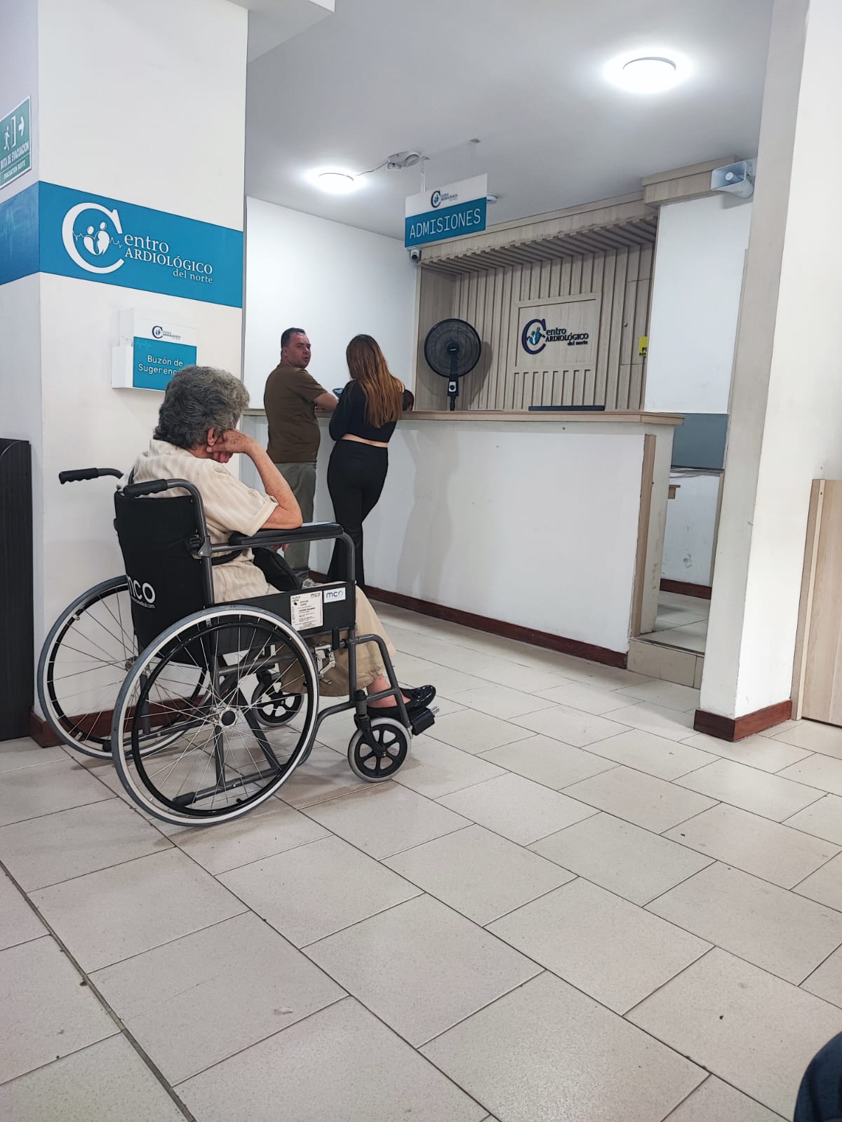 Adulta mayor en silla de ruedas esperando en admisiones de un centro médico